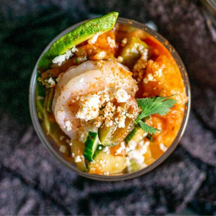 overhead shot of a glass of mexican shrimp cocktail surrounded by blue corn tortilla chips.