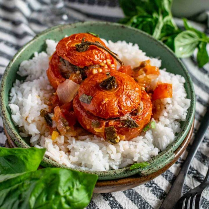 Two stuffed tomatoes on a bed of rice.