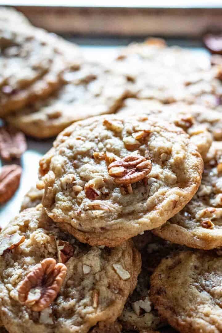 Maple pecan cookies on a silver baking tray stacked all over the place.