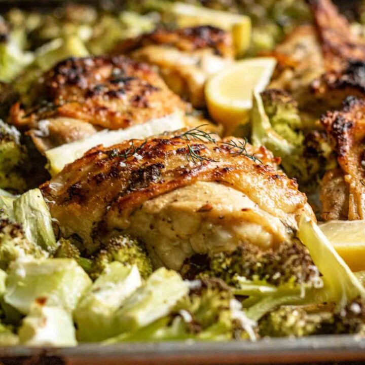 Lemon dill sheet pan chicken thighs nestled on a pan between broccoli florets.
