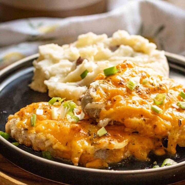 2 pork chops on a black plate with mashed potatoes.