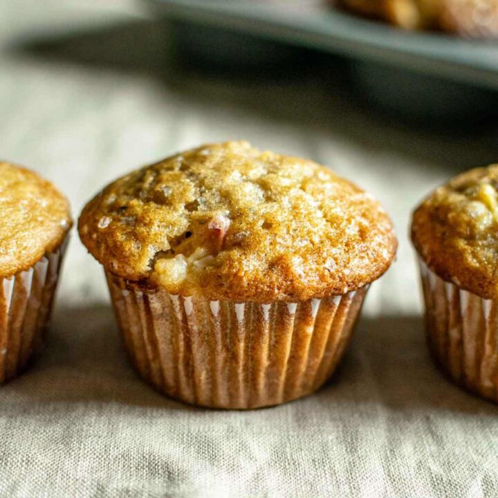 Three muffins in a row with one full peach ginger muffin in frame.
