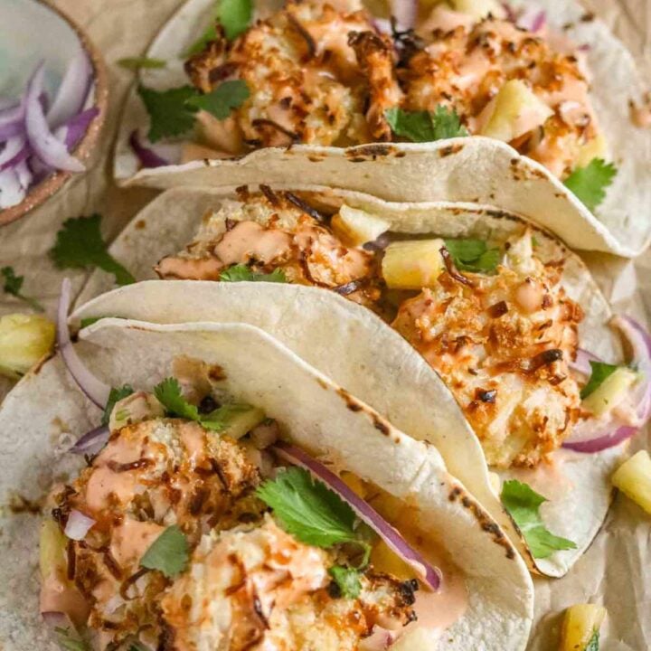 close up of three coconut shrimp tacos.