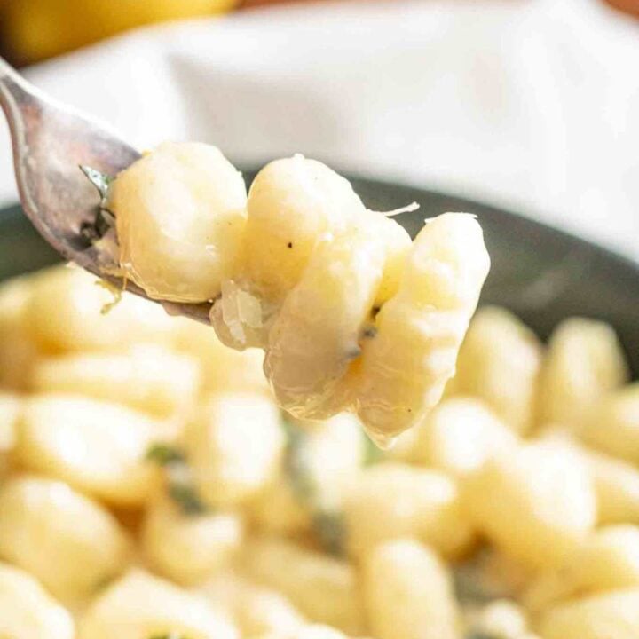 Four gnocchi al limone on a fork hovering above the bowl.
