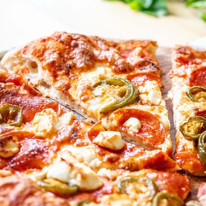 A slice of pepperoni pizza with jalapenos and goat cheese and hot honey.