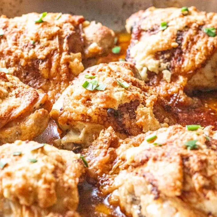 Several garlic parmesan chicken thighs in a stainless steel skillet.