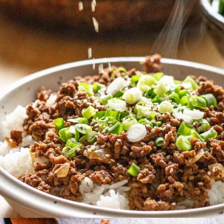 Sprinkling sesame seeds on a bowl of ground beef bulgogi.